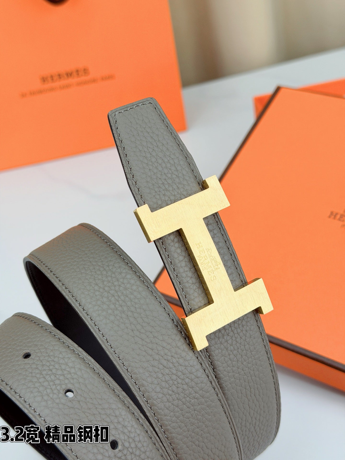 Grey leather belt with gold-tone H buckle and folded strap end