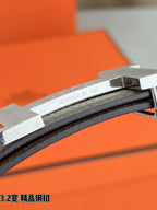 Engraved metal H buckle detail on grey leather belt