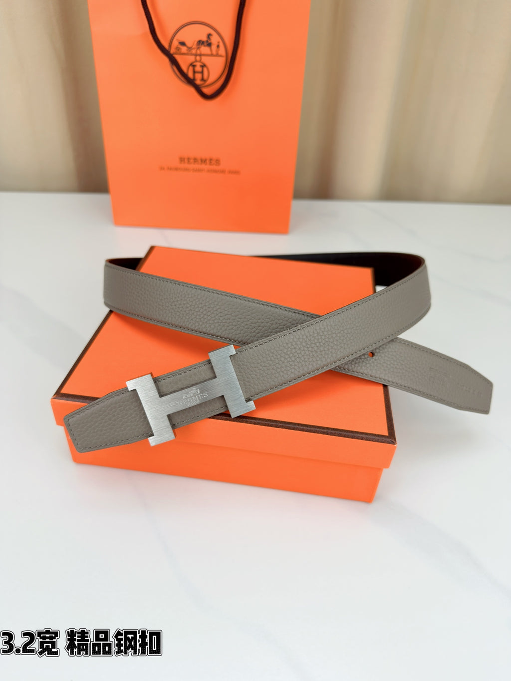 Grey leather belt with gold-tone H buckle and eyelets along strap