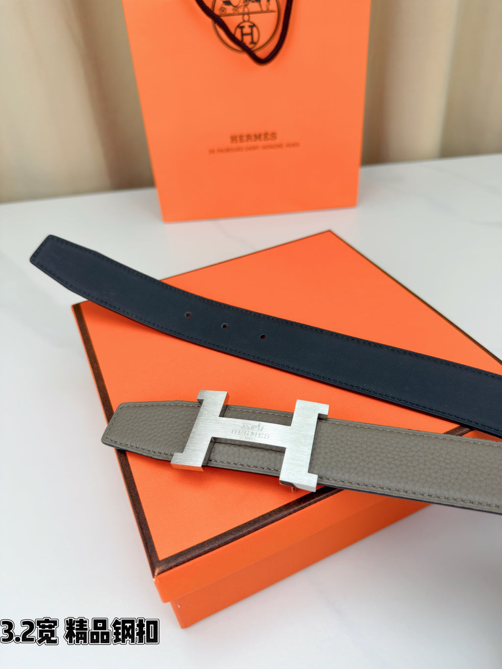 Grey leather belt with gold-tone H buckle and dark navy end section
