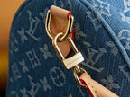 Close-up of Louis Vuitton key ring clasp on blue monogram bag strap.