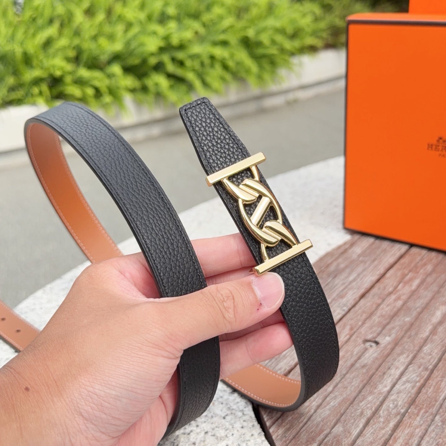Black leather belt with gold buckle and tan lining, close-up on clasp