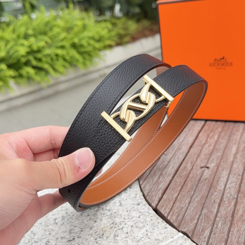 Black leather belt with gold buckle, held in hand; tan lining visible