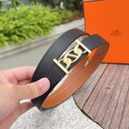 Black leather belt with gold buckle, held in hand; tan lining visible