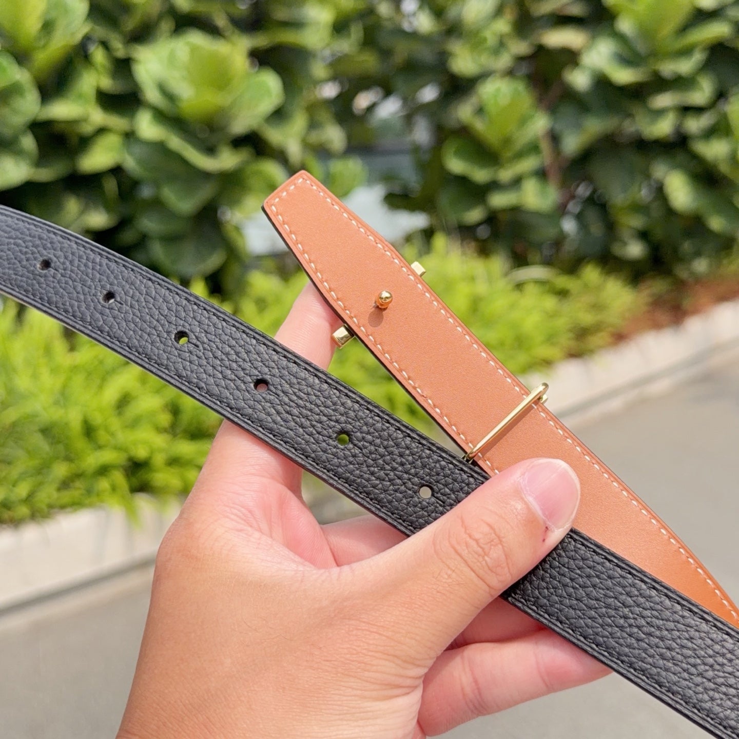 Black leather belt with punched sizing holes and gold-tone buckle hardware