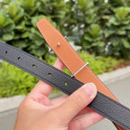 Hermes belt with black textured strap and tan lining; punched adjustment holes