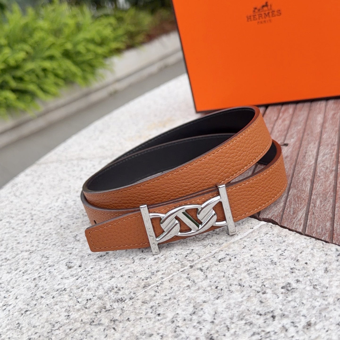 Hermes belt with tan strap, silver buckle centerpiece, black underside