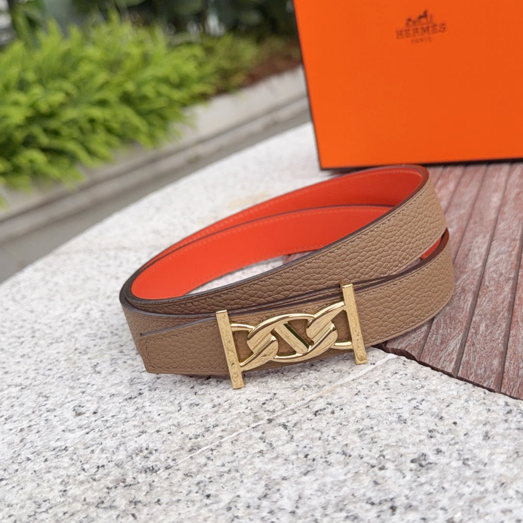 Leather belt with tan strap, orange lining, and gold logo buckle