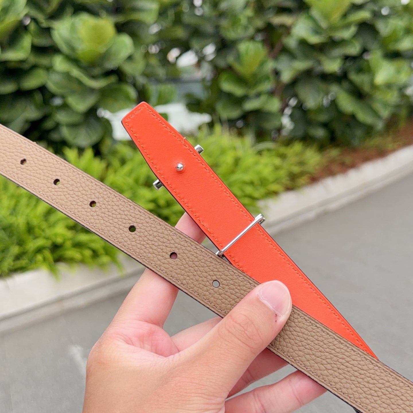 Leather belt double view: tan front with holes and orange reverse strap