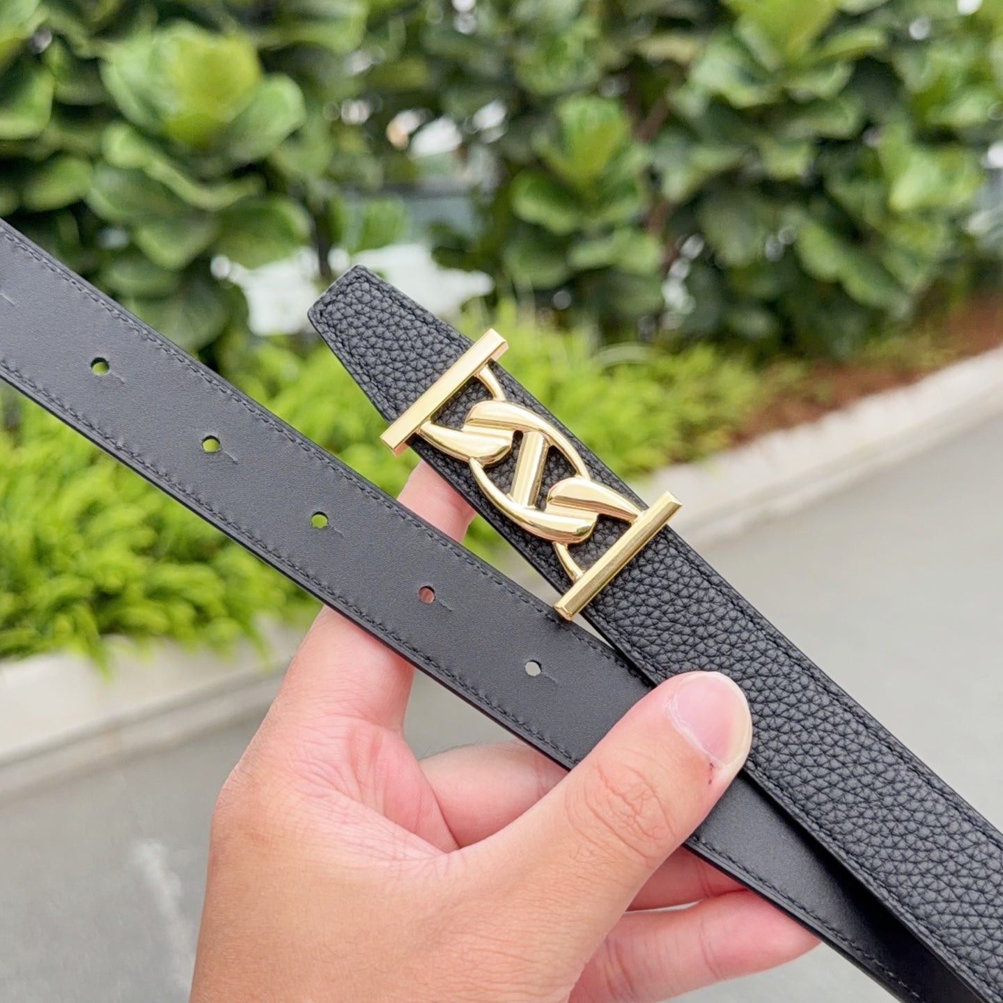 Leather belt with dark gray strap, gold-toned buckle, and punched holes
