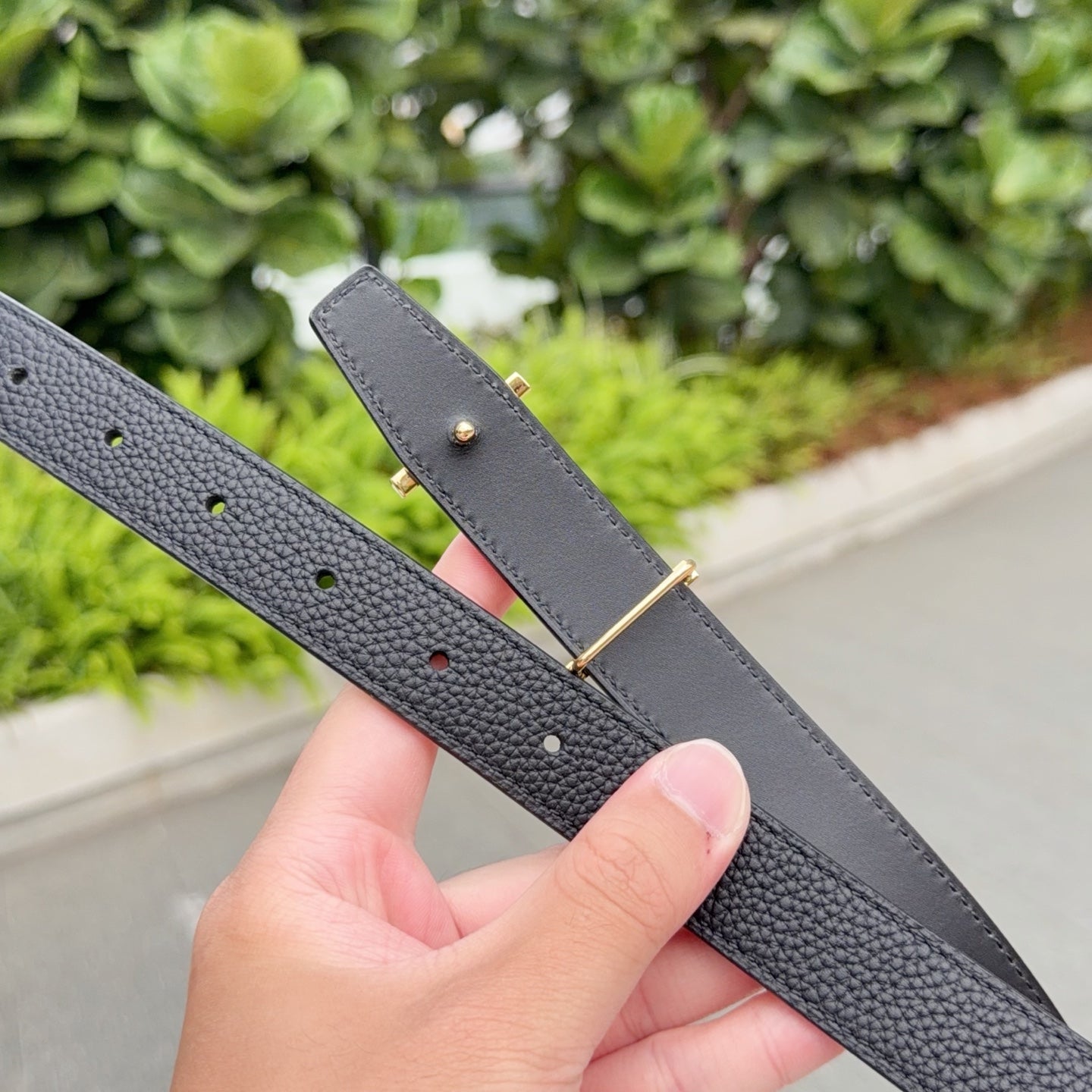 Leather belt with dark gray strap, gold-toned hardware, and hole row