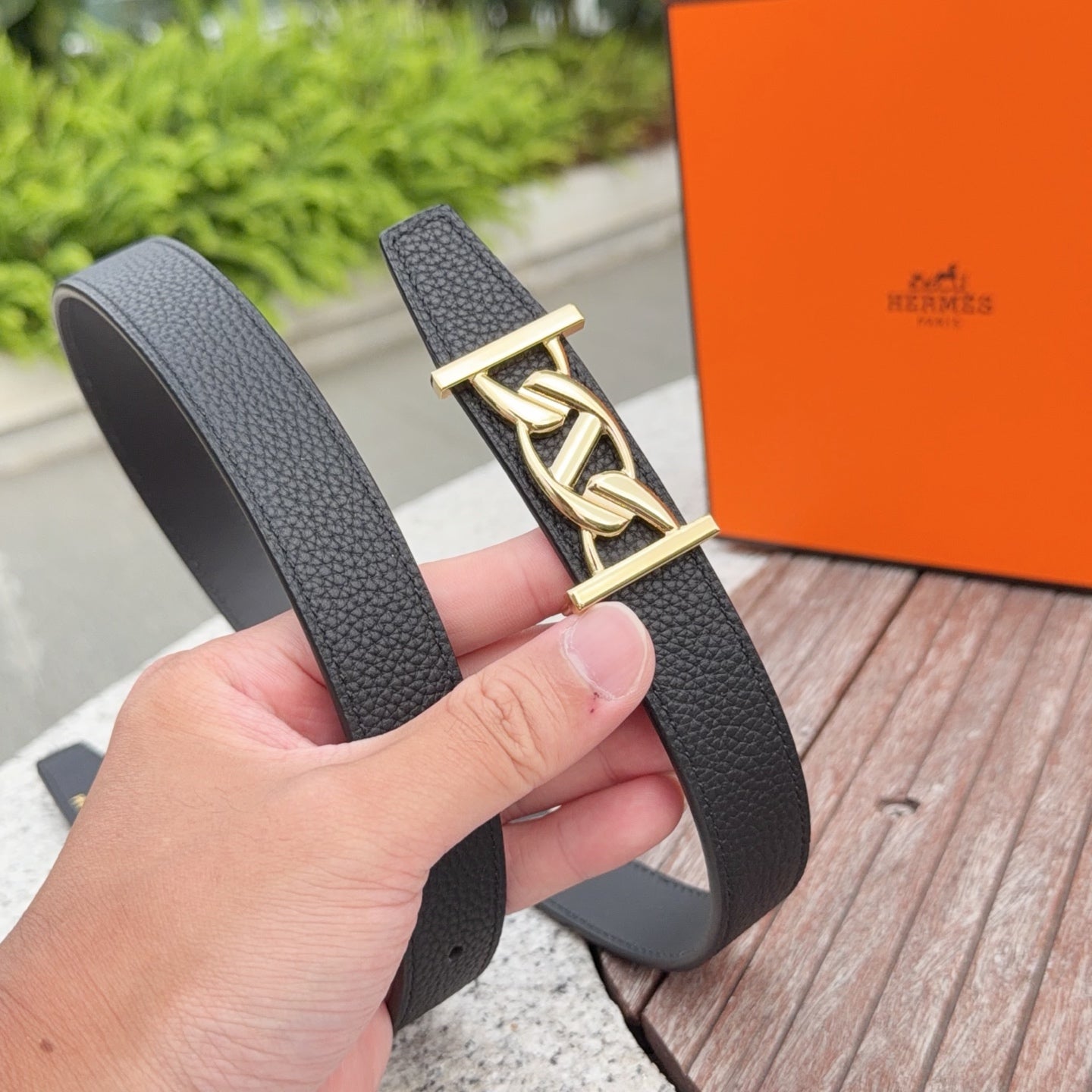 Leather belt with dark strap and gold-toned buckle clasp, side view