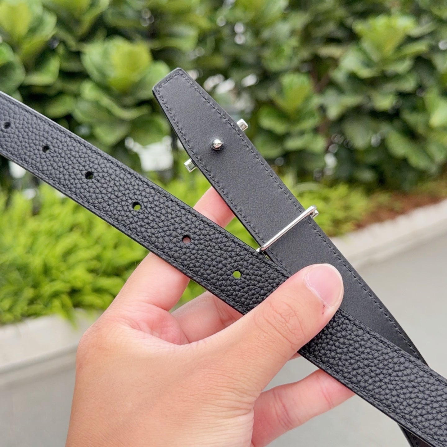 Hermes black leather belt with adjustable holes and silver pin buckle plate, close-up