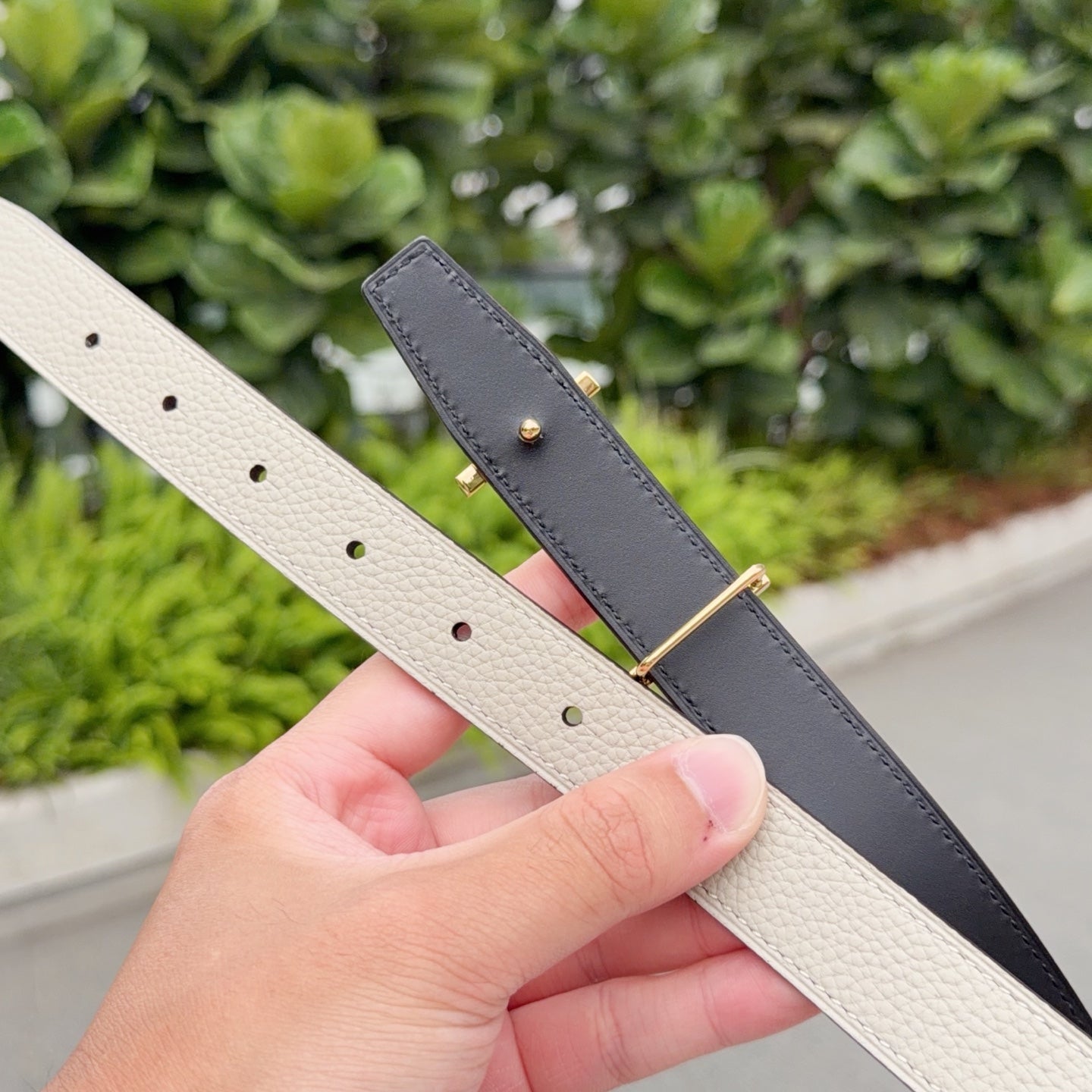 Two leather belts with gold-tone buckle hardware, one beige and one dark