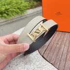 Beige leather belt close-up with gold-tone clasp buckle and dark underside