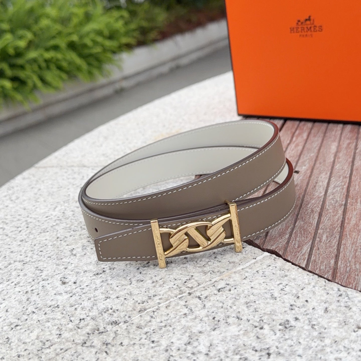 Leather belt in taupe with gold-tone buckle, stitched edges, and adjustment holes
