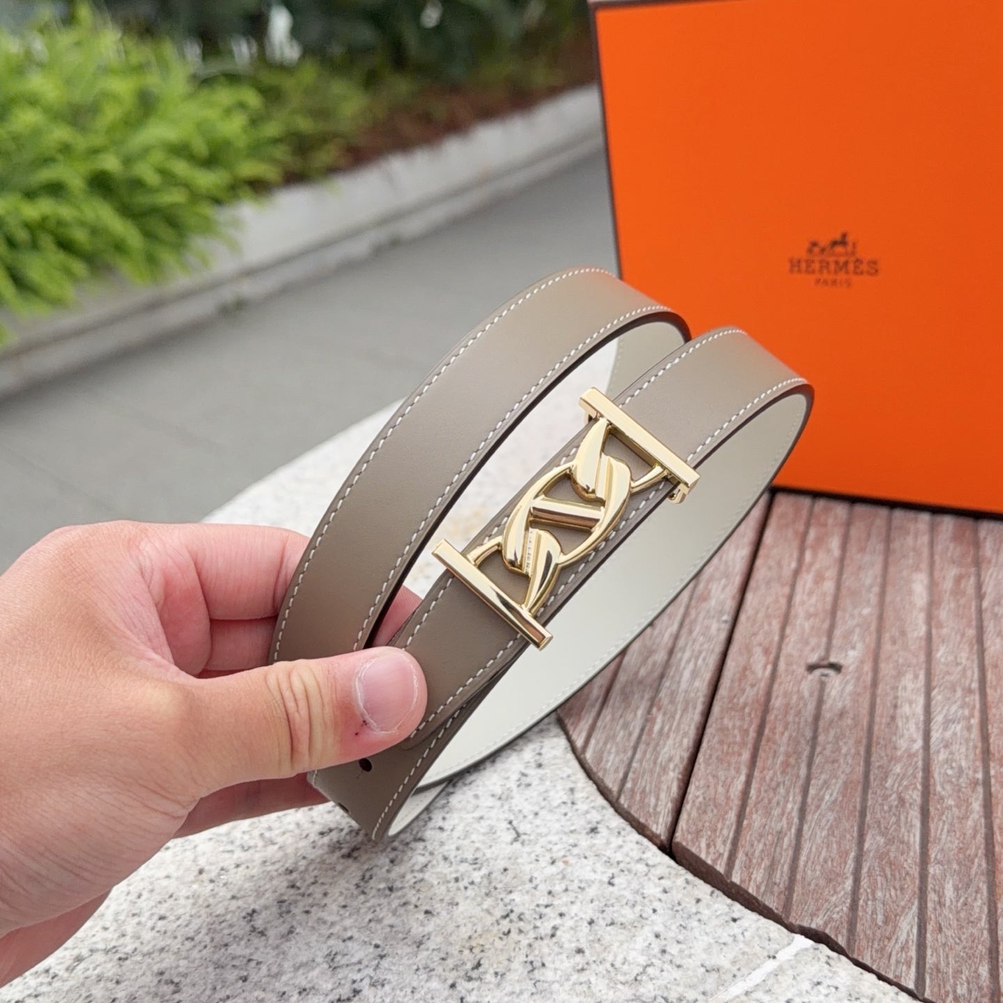 Taupe leather belt with gold buckle featuring an interlocking motif