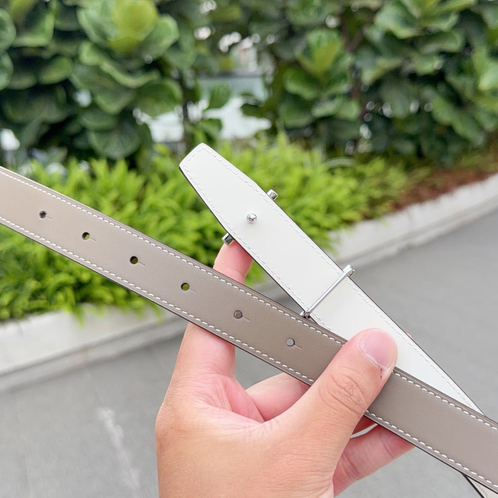 Reversible Hermes leather belt showing white and taupe sides with punched adjustment holes.