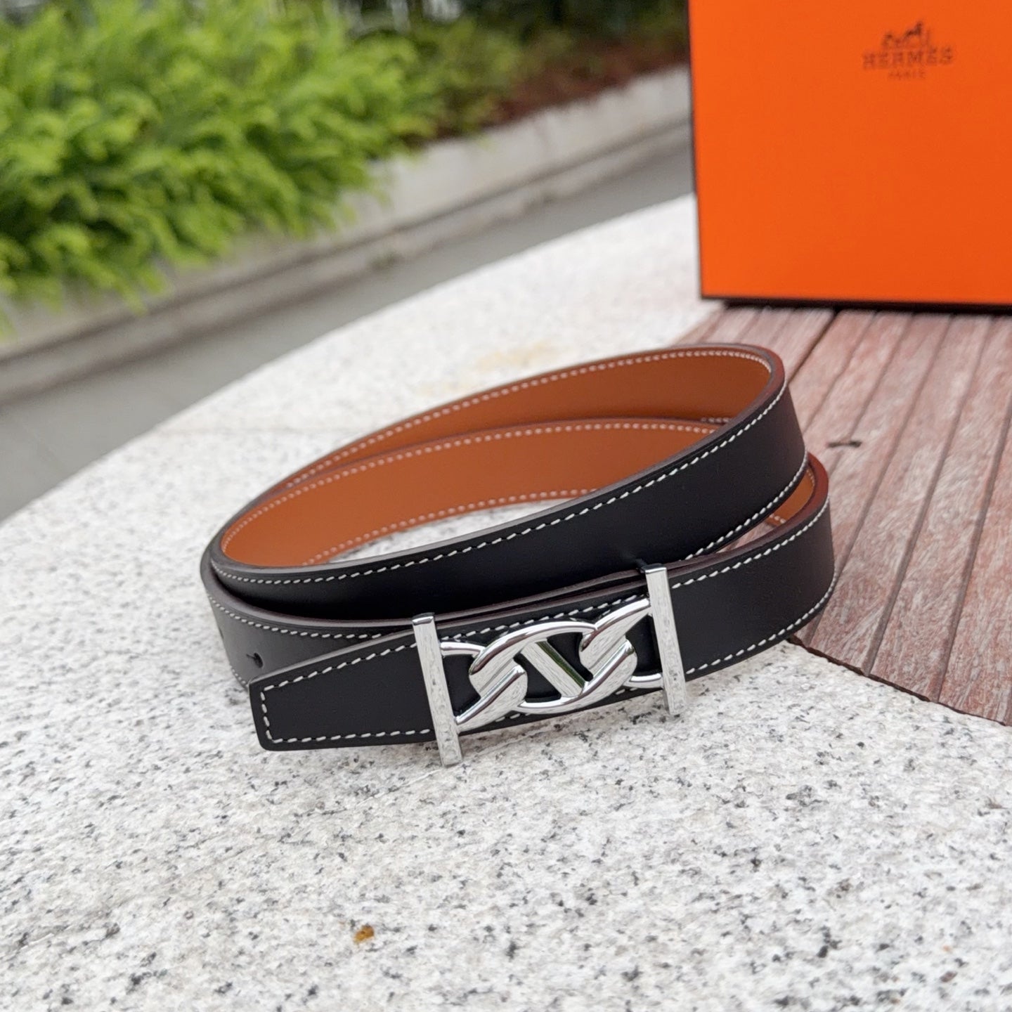 Black leather belt with tan backing and silver buckle, double-stitched trim
