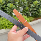 Leather belts in dark gray and tan, each with punched holes and white stitching