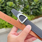 Hermes belt detail with silver buckle, dark strap and tan keeper strap