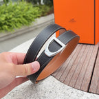 Hermes belt held close-up with silver buckle, dark strap and tan lining