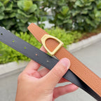Tan leather belt with gold buckle; dark gray belt strap beneath.