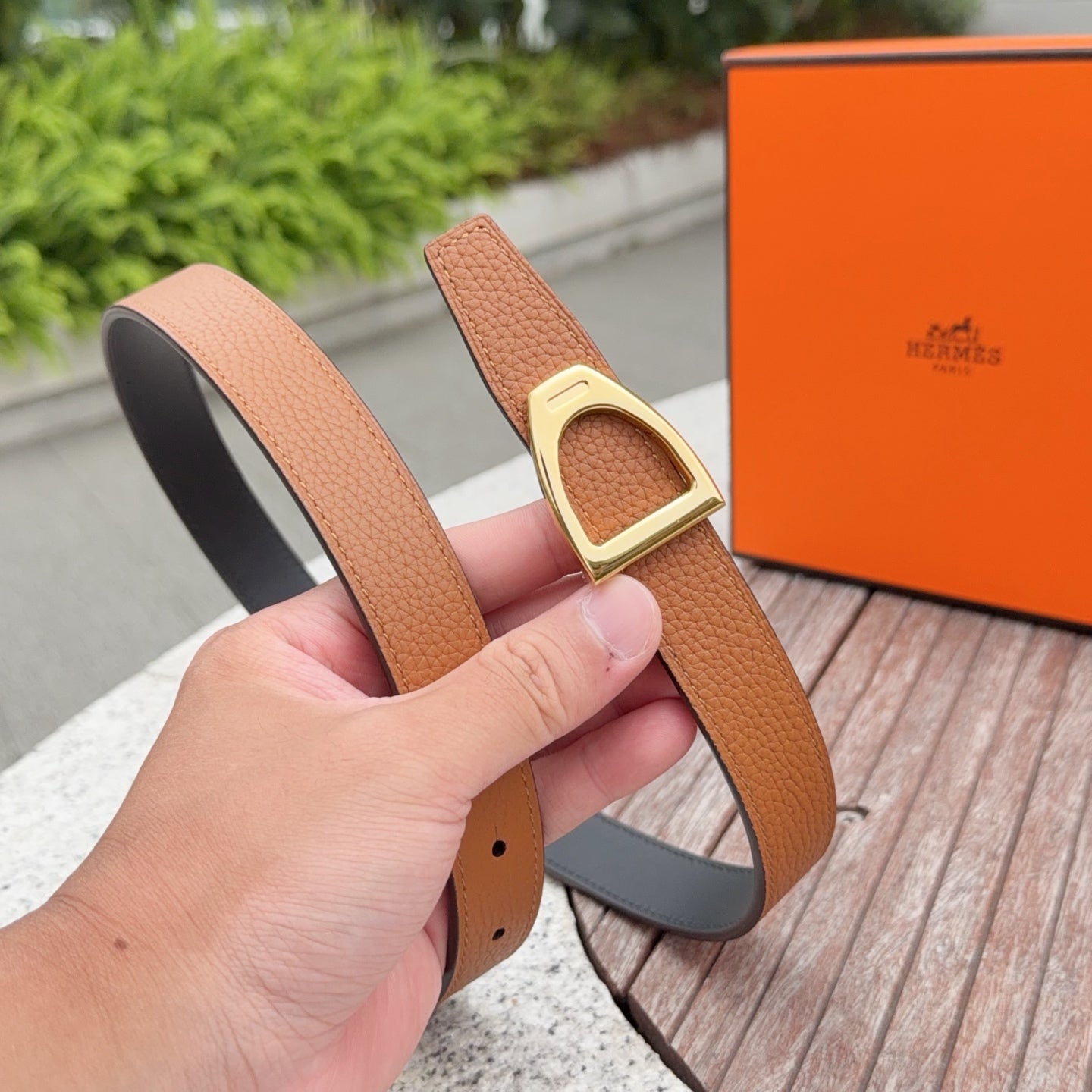 Tan leather belt with gold buckle, black lining, and row of punched holes.