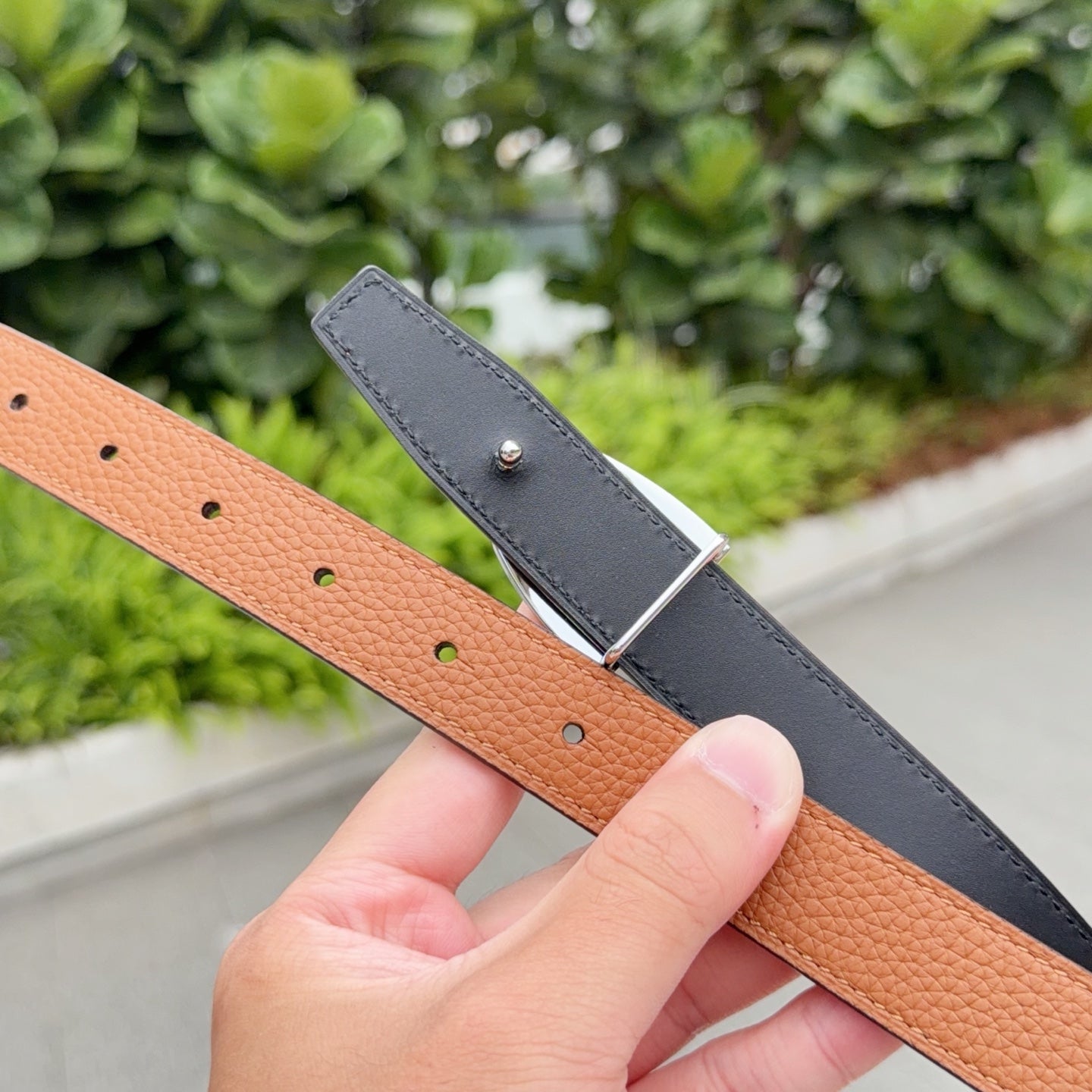 Leather belt close-up with orange-brown strap and dark gray matching strap