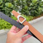 Leather belt with orange-brown strap and silver buckle over dark gray belt strap