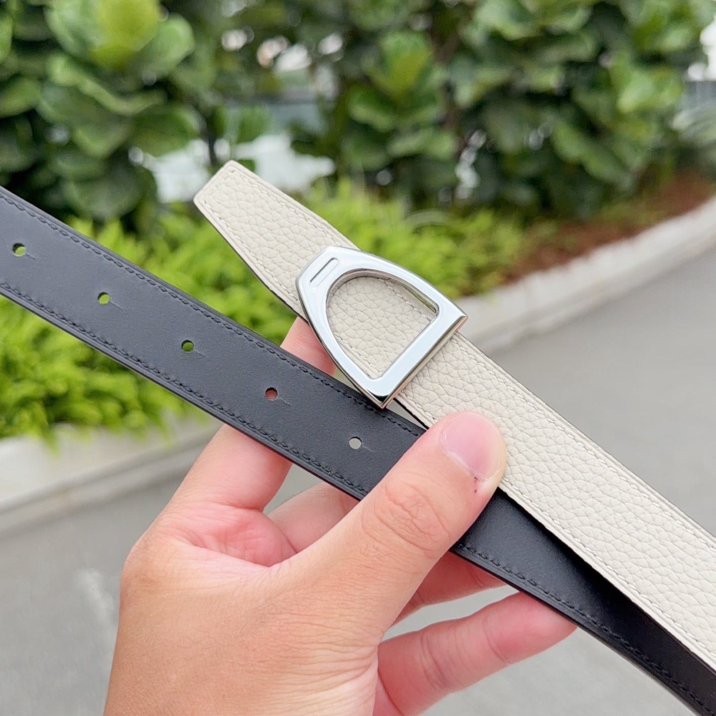 Light beige leather belt with silver buckle and dark strap underside