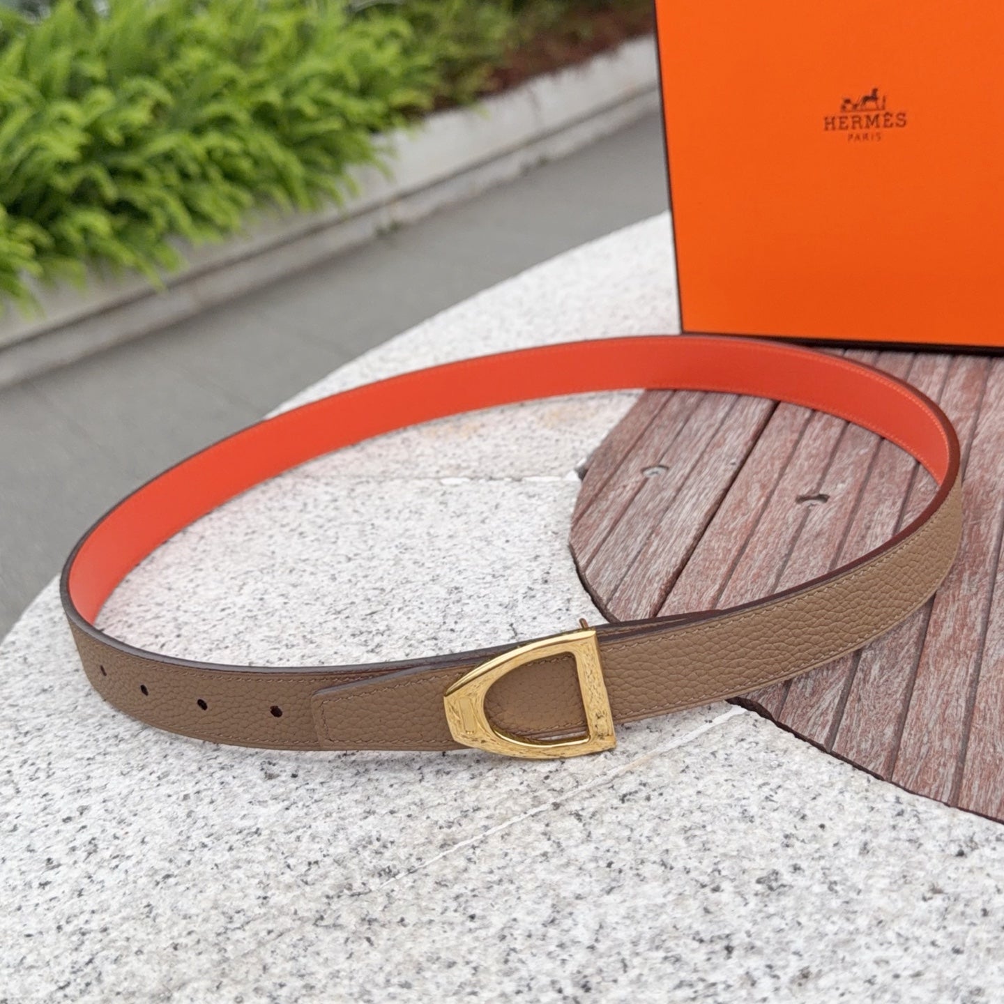 Tan leather belt with gold buckle, orange lining, and punched sizing holes