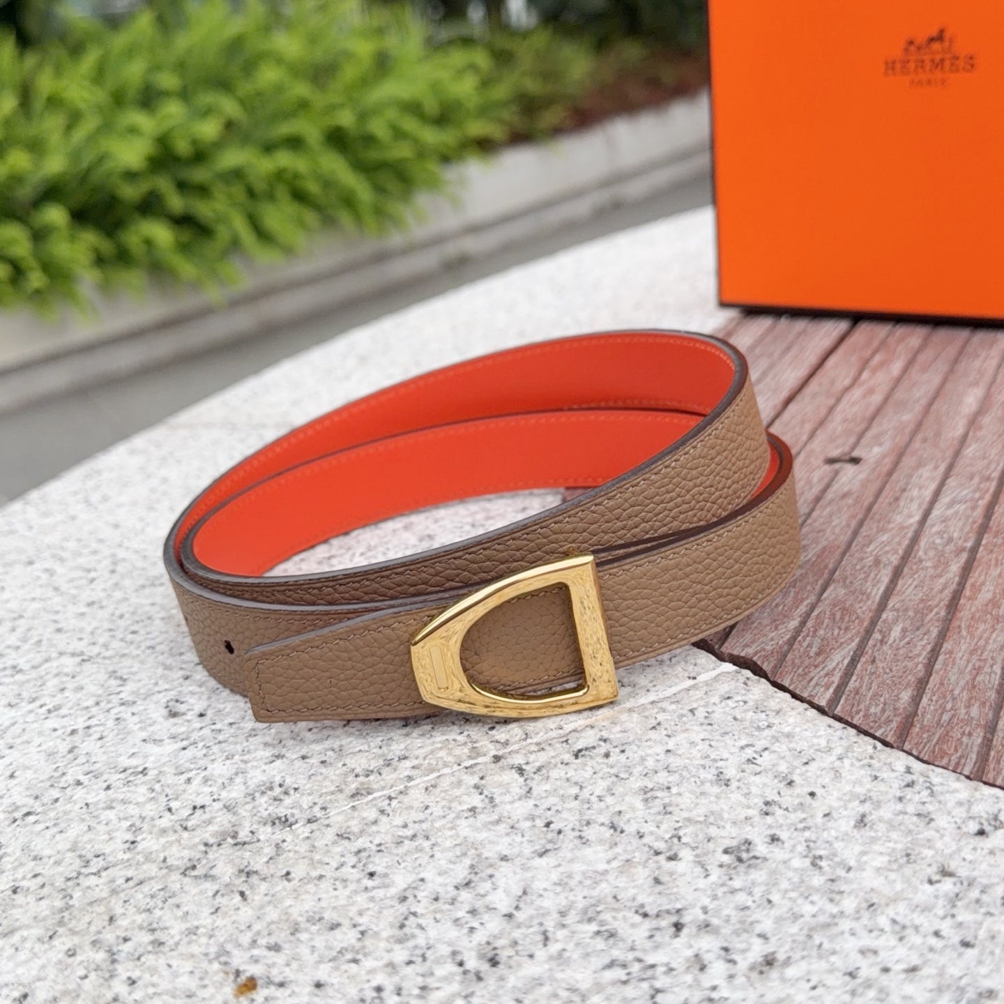 Tan leather belt with gold buckle and orange inner lining, shown from side angle