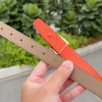 Tan leather belt with punched sizing holes, gold pin on orange strap