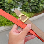 Tan leather belt with gold buckle and bright orange underside, with punched holes