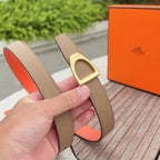 Tan leather belt with gold-tone rectangular buckle and orange underside, held upright