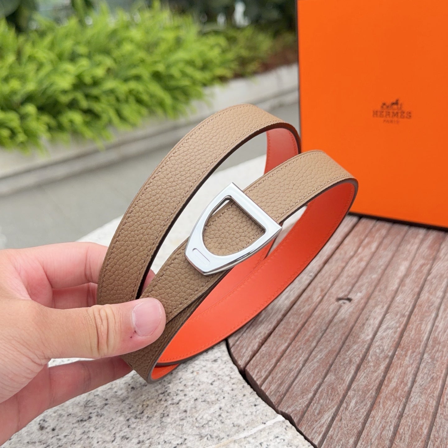 Brown leather belt with silver buckle and orange underside