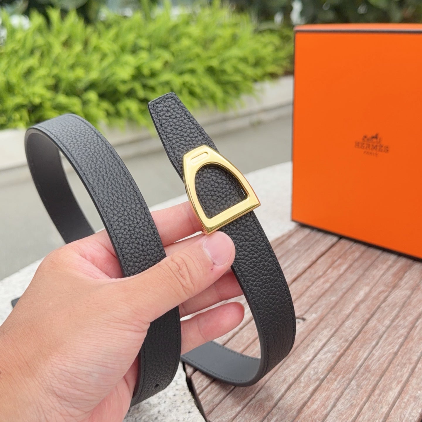 Black leather belt with gold-tone buckle, shown from side angle