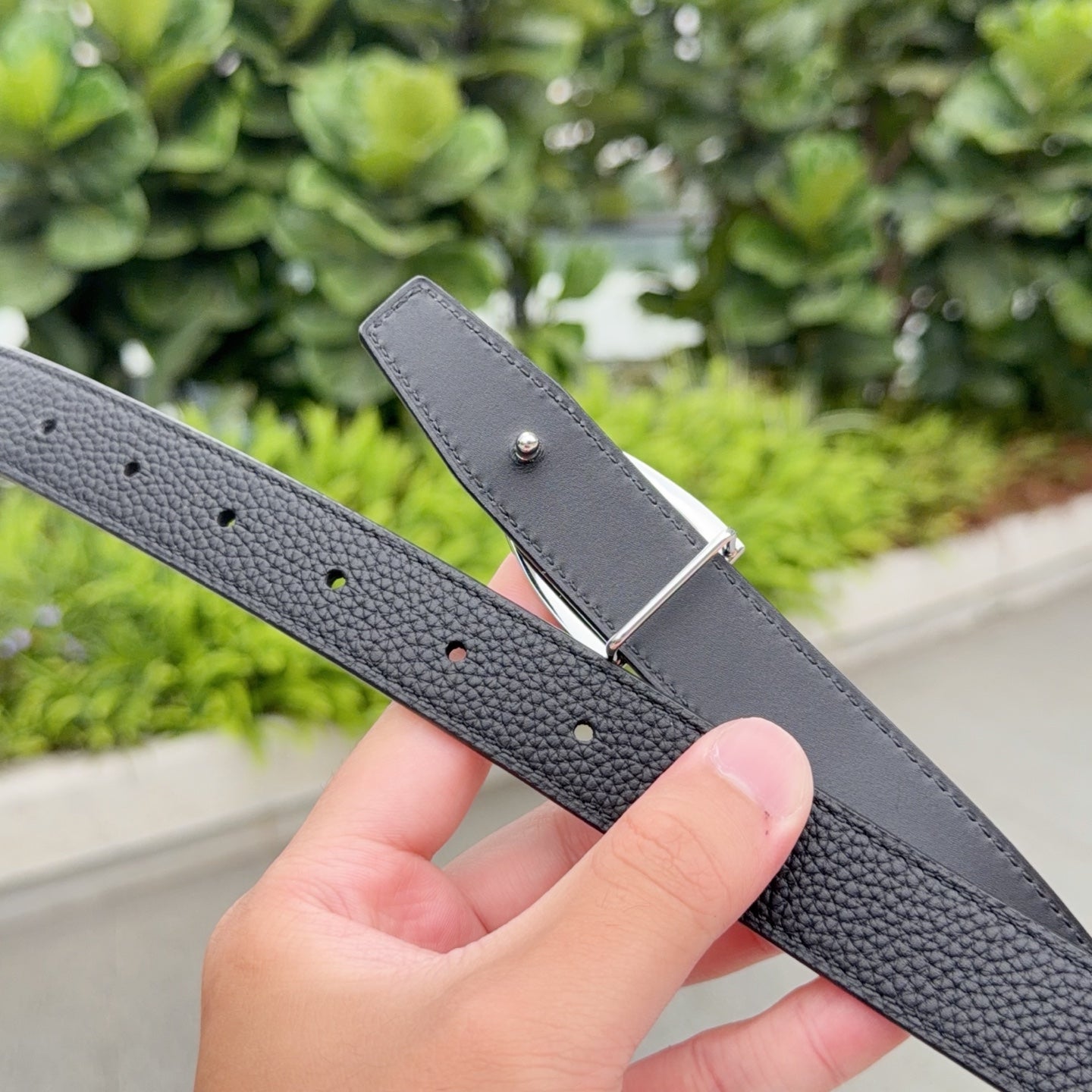 Gray leather belt with silver buckle tip and visible adjustment holes
