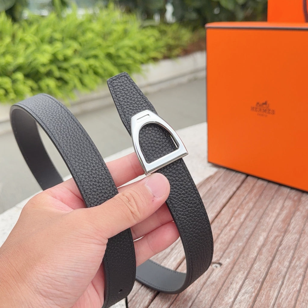 Dark leather belt with silver buckle, held up in front of a box
