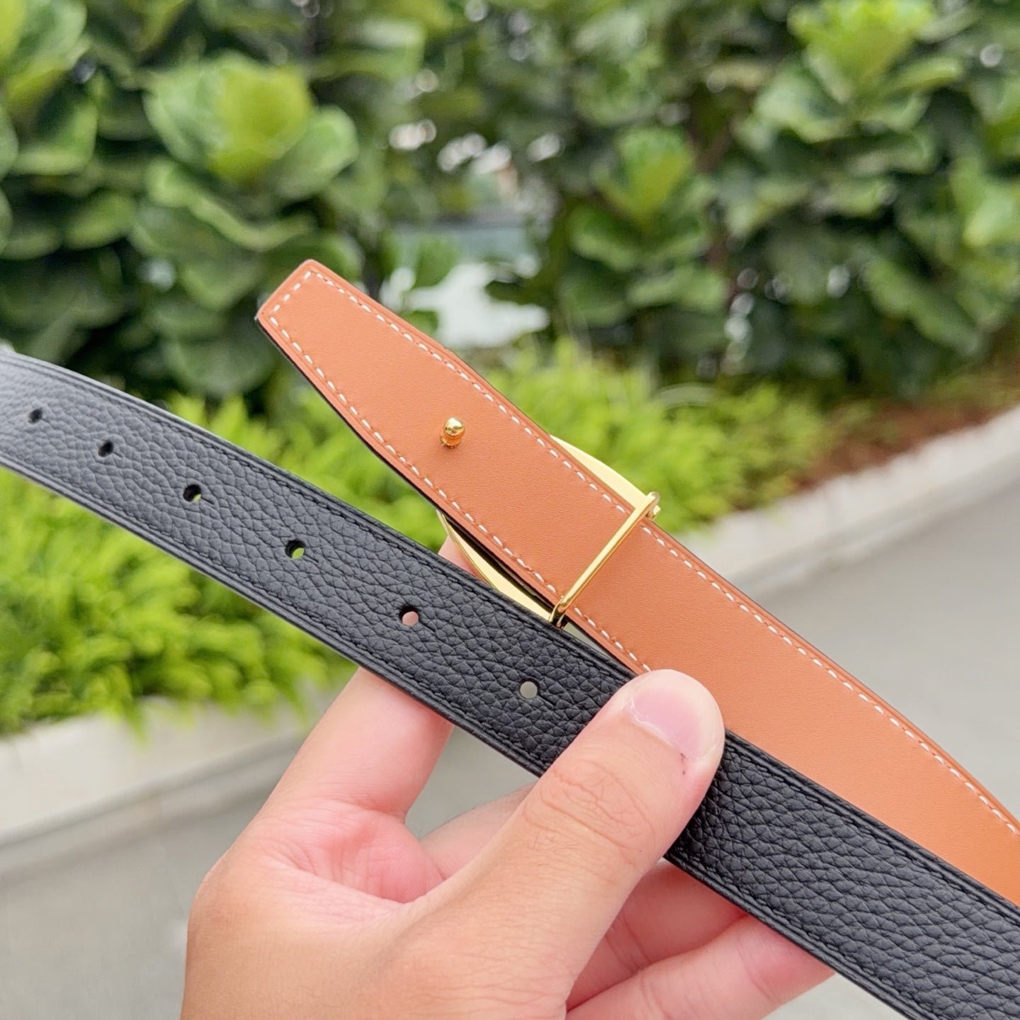 Leather belt close-up: black strap with pin holes and tan leather underside