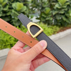 Leather belt with black strap and gold buckle, tan reverse with stitching holes