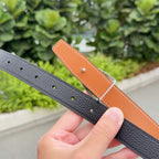 Black leather belt with punched holes; tan lining strap with silver prong