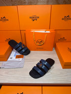 Dark blue leather slide sandals with two wide straps and metal buckle hardware