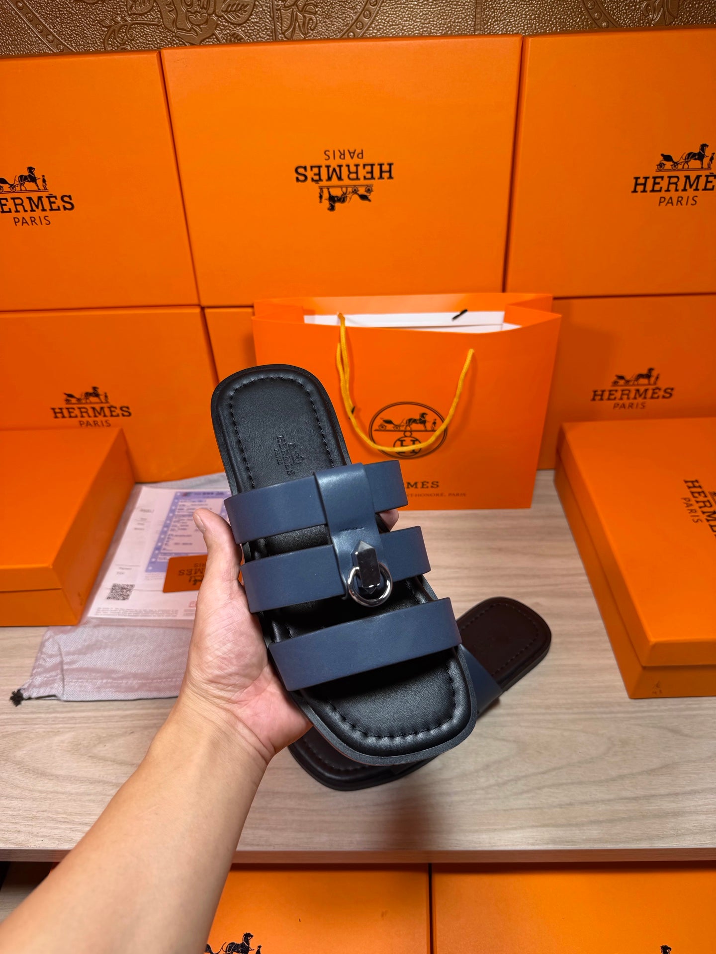Leather slide sandals with dark blue upper and visible treaded sole in hand