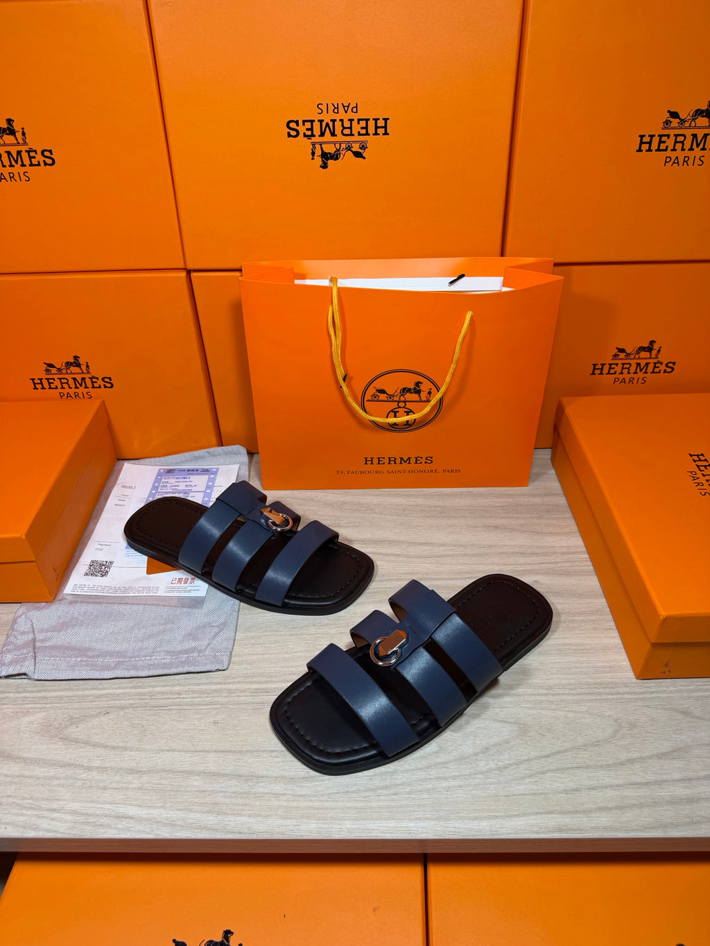 Two dark blue leather slide sandals with double straps and circular metal buckles