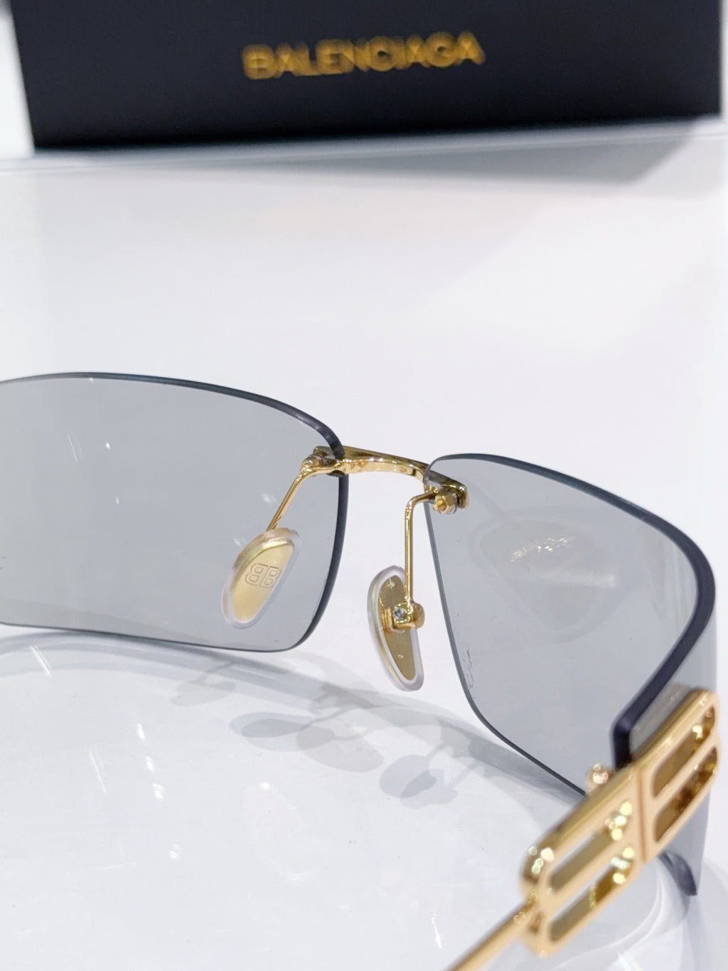 Balenciaga glasses with dark lenses and gold-tone frame, close-up