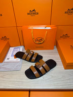 Hermes slide sandals with tan straps, dark leather lining, and silver buckle.