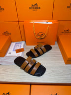 Hermes sandals featuring tan strap bands and a silver buckle over dark footbed.