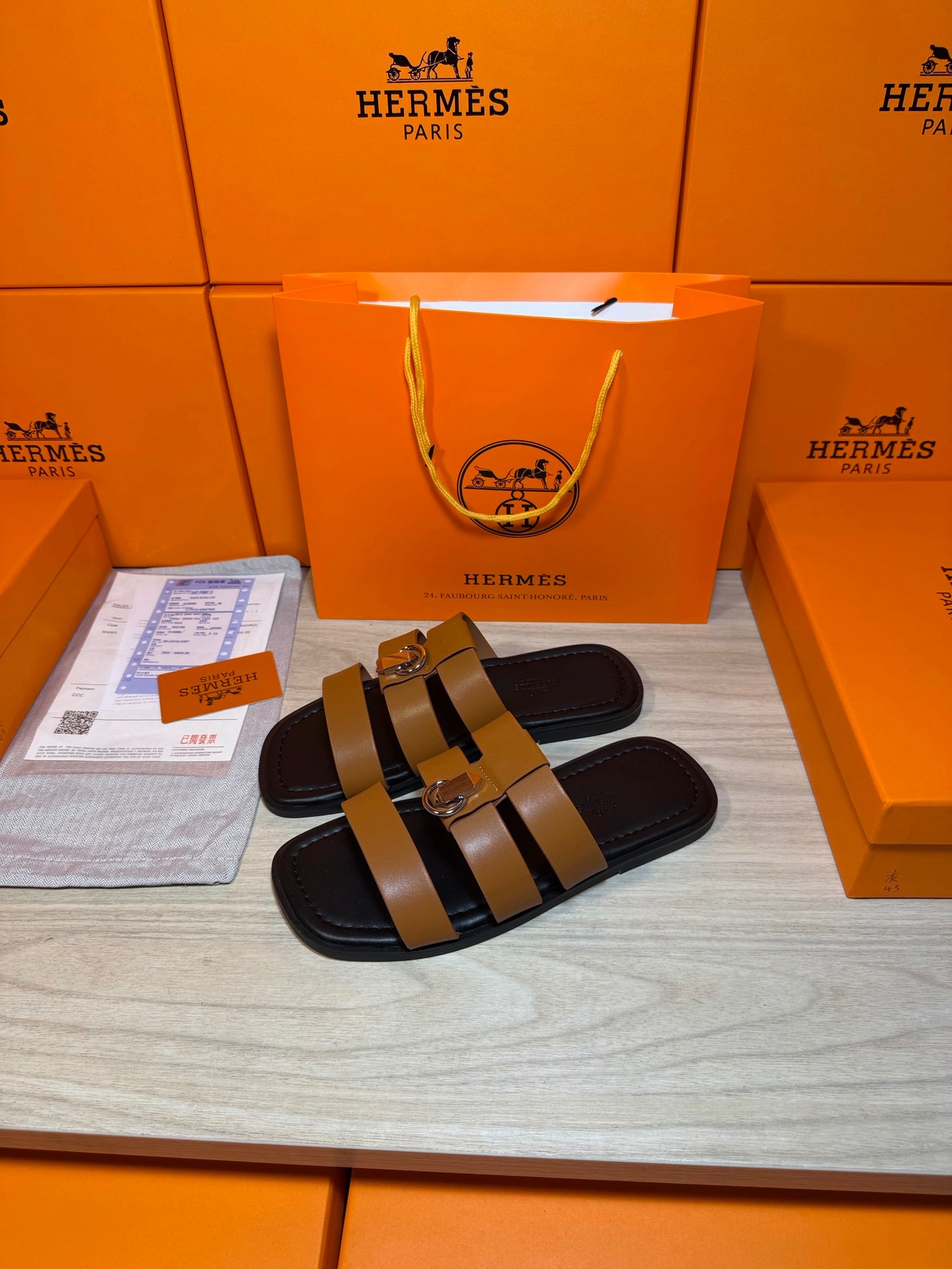 Hermes slide sandals, tan and dark leather with silver buckle detail.